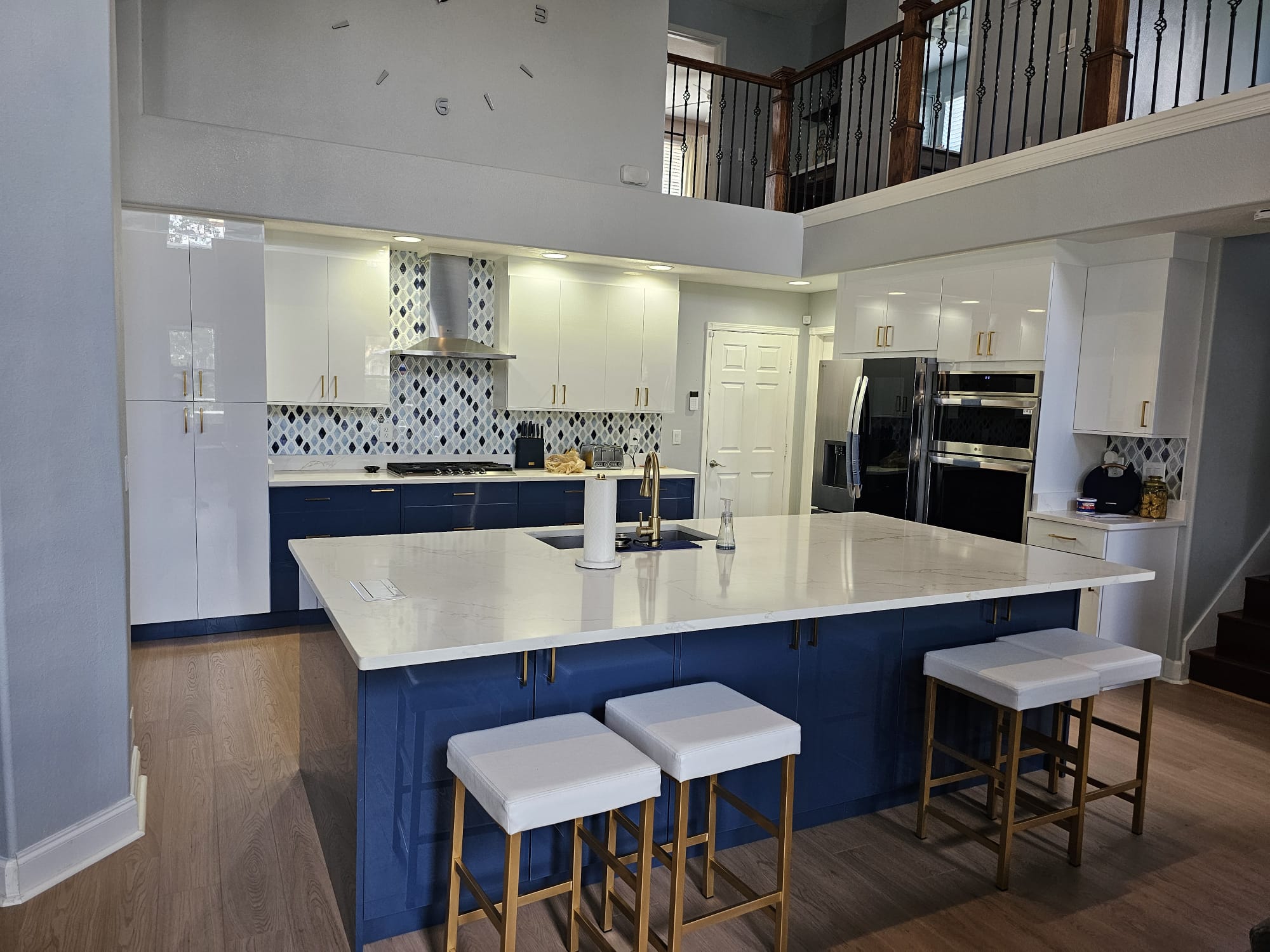 High-gloss white kitchen with a navy island and diamond backsplash